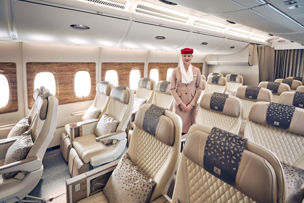 Cabine Premium Economy da Emirates, com assistente de bordo no corredor